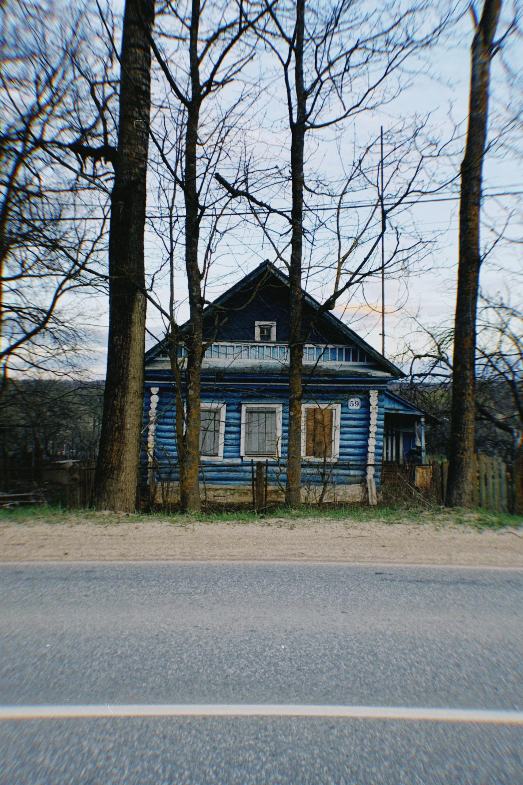 A charming blue wooden house with a rustic look in a quiet rural area, captured in early spring.
