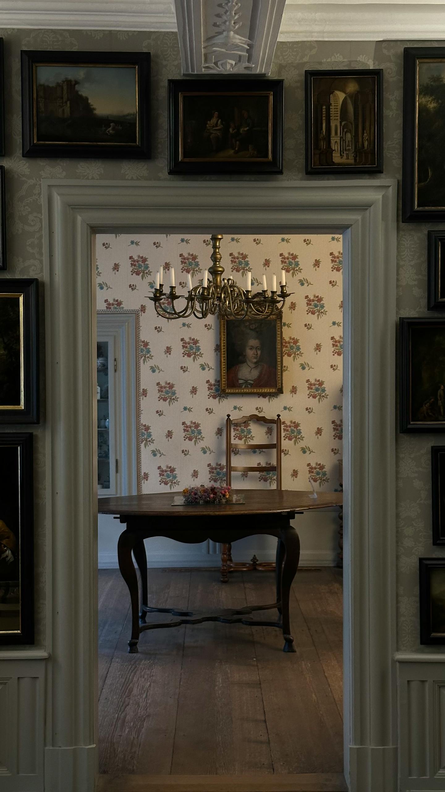 Elegant vintage room with chandelier, art, and antique furniture in a classic setting.