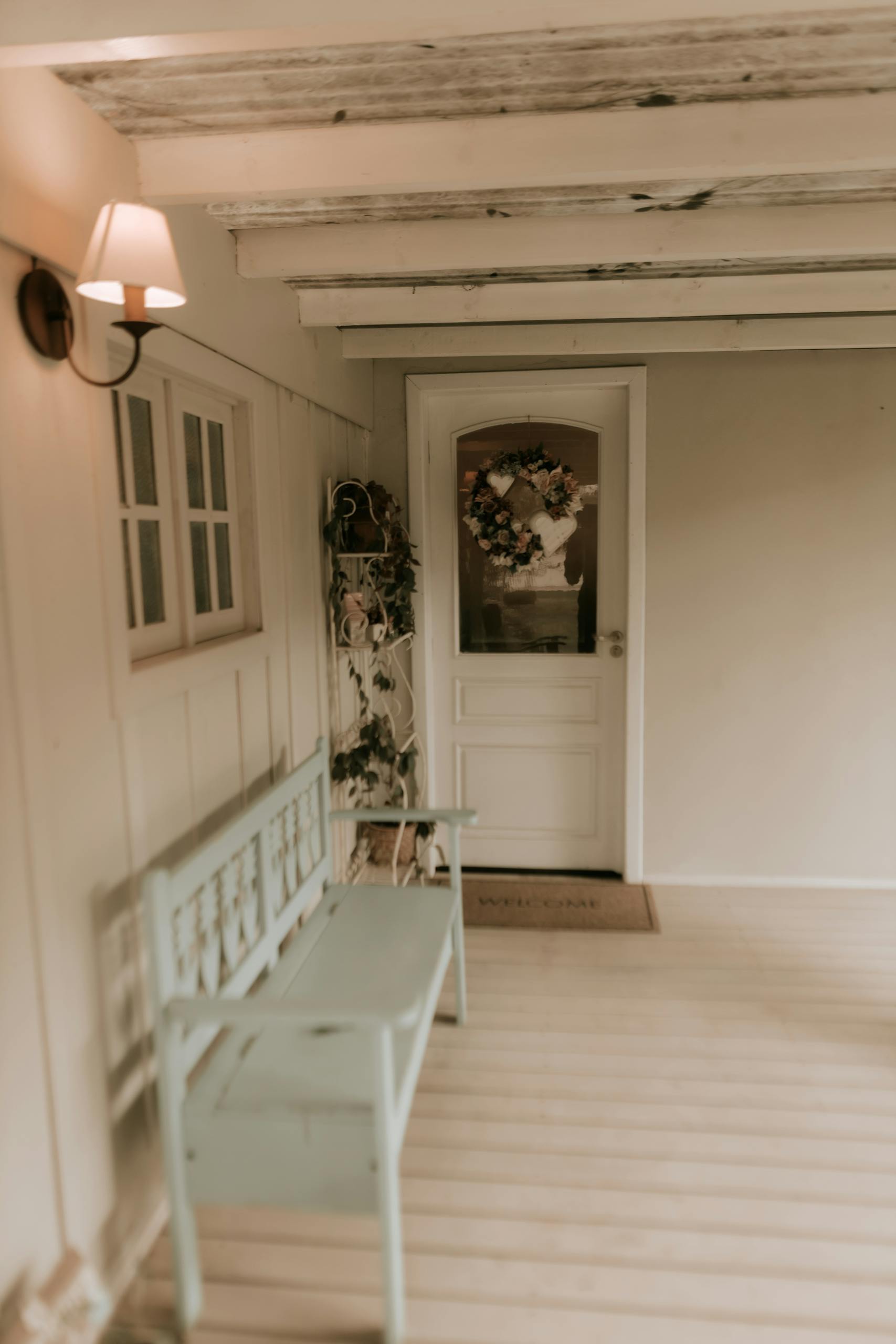Inviting rustic porch with a wreath-adorned door and elegant bench, perfect for a warm ambiance.